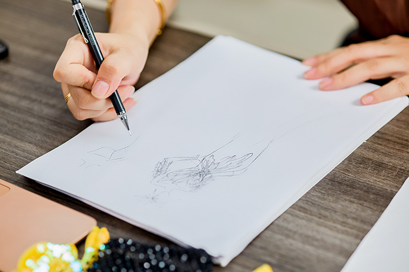 رسم تخطيطي راقي لمصمم على مكتب بجانب مواد الخرز